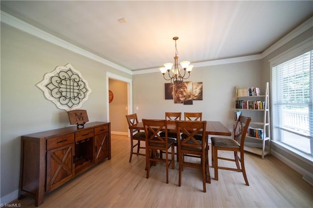 dining space with light wood-type flooring, crown molding, and a notable chandelier