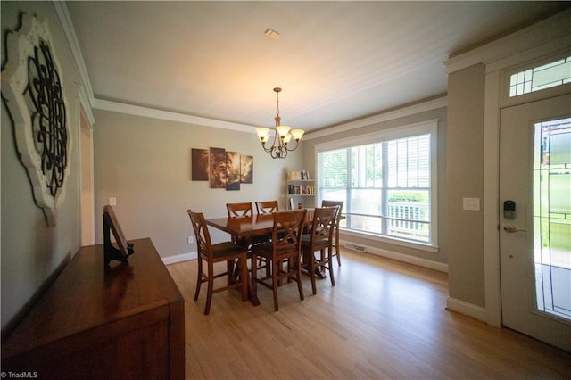 dining room featuring ornamental molding, light hardwood / wood-style floors, and a notable chandelier