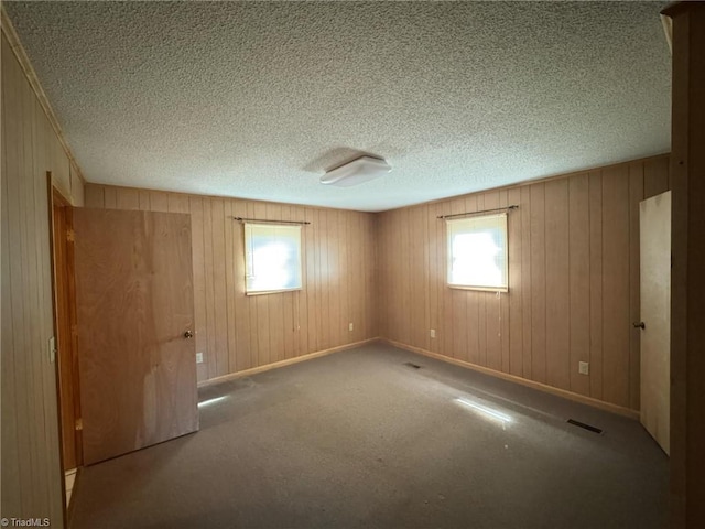 carpeted empty room with baseboards, visible vents, and a textured ceiling