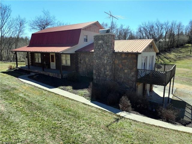 view of front of house with a front yard, a porch, a gambrel roof, stone siding, and metal roof