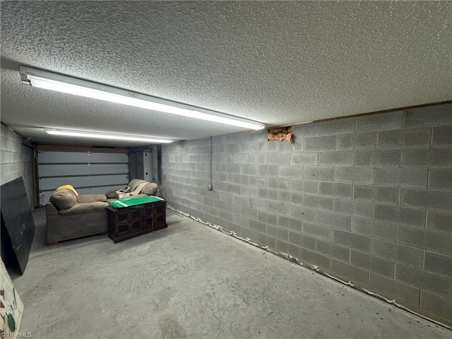 finished below grade area with a garage, a textured ceiling, and concrete block wall