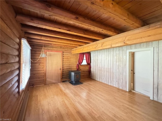 unfurnished living room featuring beamed ceiling, wood ceiling, a wood stove, and wood finished floors