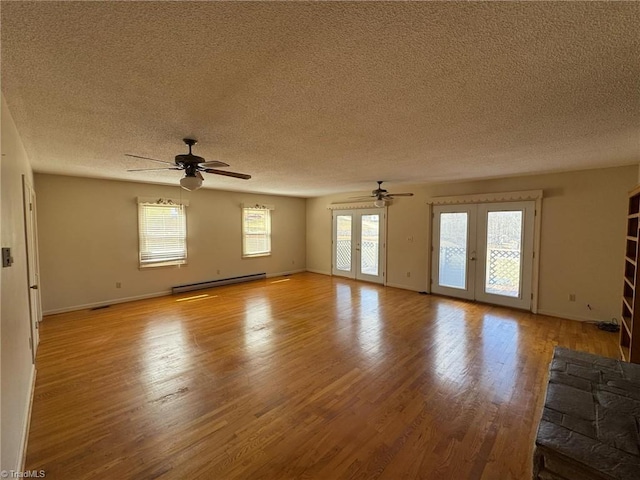 unfurnished living room featuring french doors, a textured ceiling, a baseboard heating unit, and light wood-style flooring