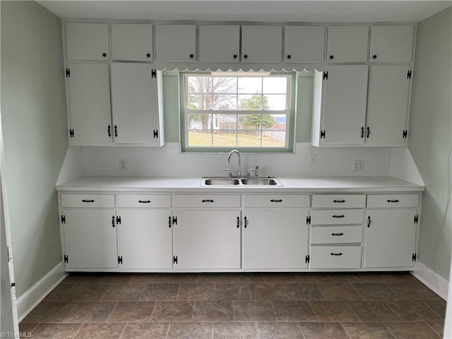 kitchen featuring white cabinets, light countertops, and a sink