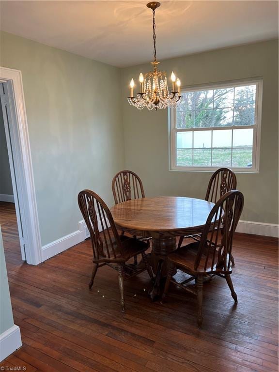 dining area featuring dark wood-type flooring, a notable chandelier, and baseboards