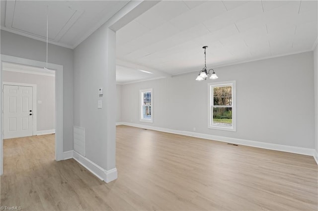 empty room with an inviting chandelier, light hardwood / wood-style flooring, and crown molding