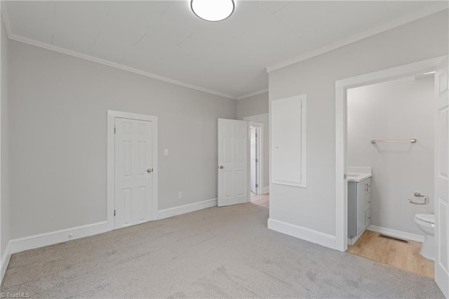 unfurnished bedroom with crown molding, light carpet, and ensuite bath