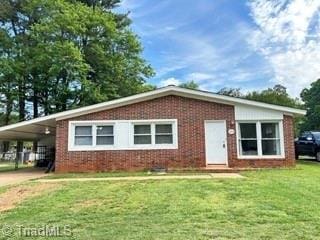 view of front of property featuring brick siding, a front lawn, a carport, and concrete driveway