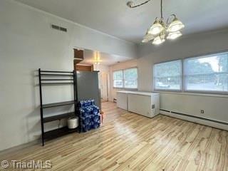 unfurnished dining area with a chandelier, wood finished floors, and a baseboard heating unit
