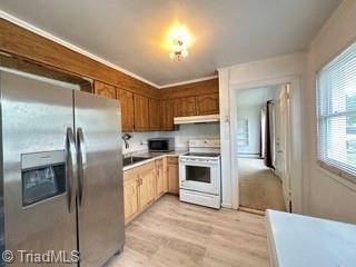 kitchen with stainless steel appliances, under cabinet range hood, light wood-style floors, and light countertops
