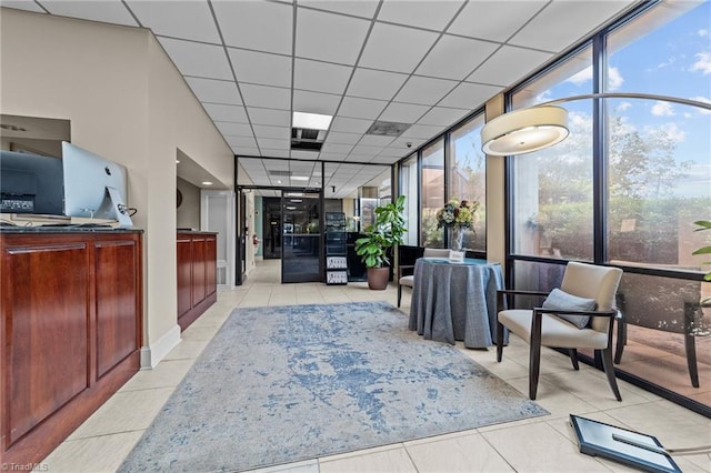 interior space with a drop ceiling, light tile patterned floors, and expansive windows