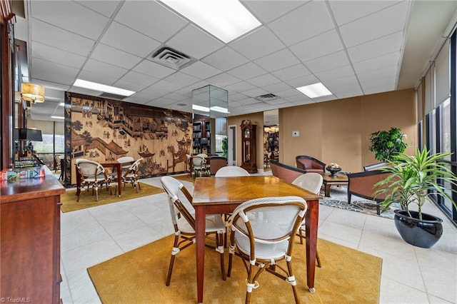 tiled dining space with a drop ceiling