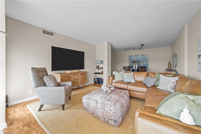 living room with light parquet floors, a textured ceiling, and track lighting