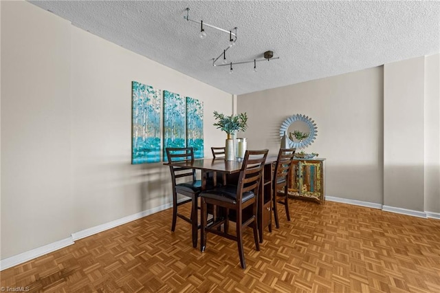 dining space with track lighting, a textured ceiling, and parquet floors