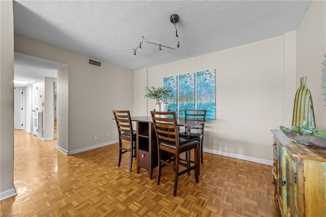 dining area featuring a textured ceiling and light parquet flooring