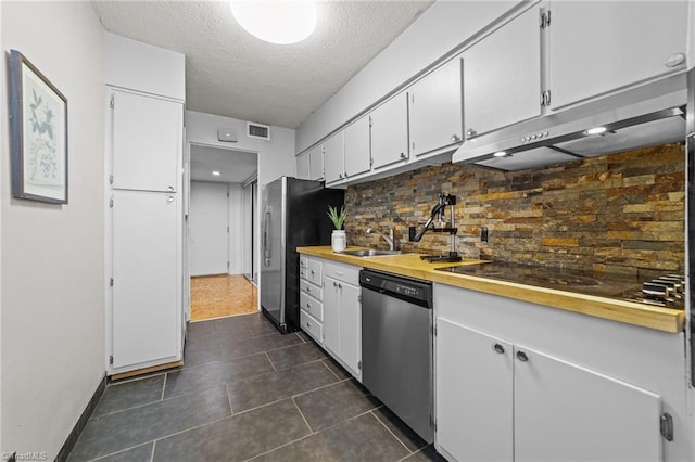 kitchen with appliances with stainless steel finishes, dark tile patterned flooring, white cabinets, backsplash, and sink