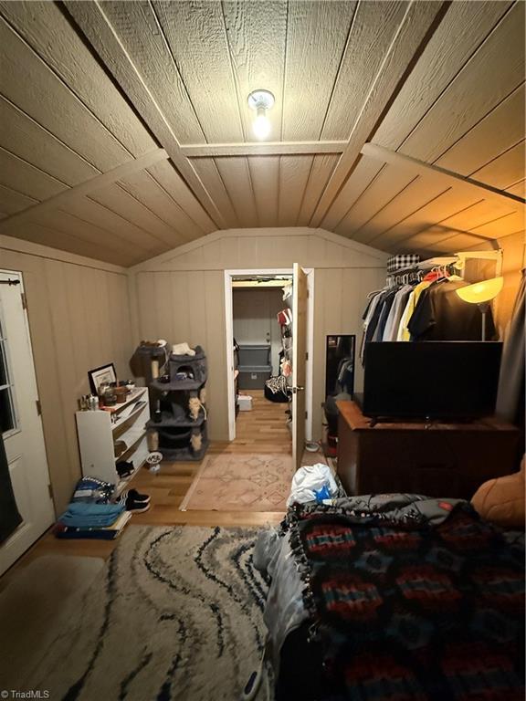 bedroom with lofted ceiling, wooden walls, hardwood / wood-style floors, and wooden ceiling