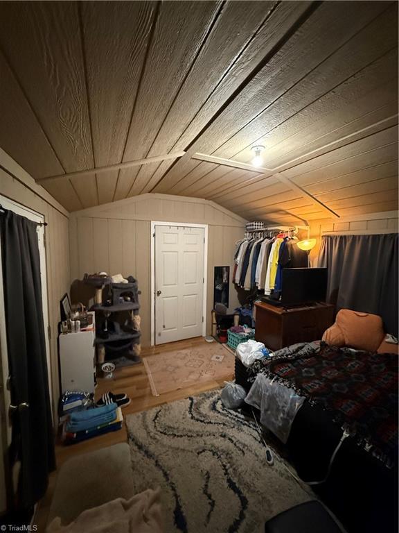 bedroom featuring wood walls, lofted ceiling, and wooden ceiling