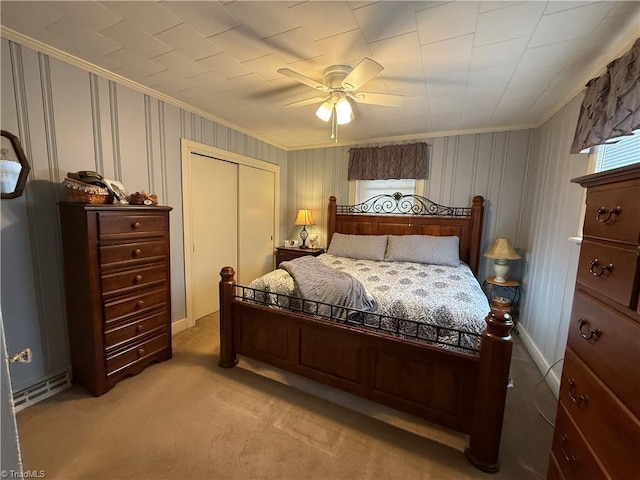 carpeted bedroom featuring ornamental molding, a closet, and ceiling fan