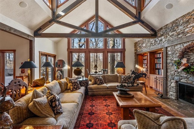 living room with a wealth of natural light, a textured ceiling, a stone fireplace, and high vaulted ceiling