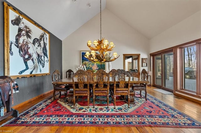 dining space featuring a notable chandelier, high vaulted ceiling, and hardwood / wood-style flooring