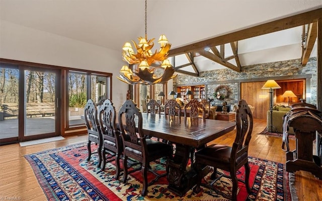 dining area featuring vaulted ceiling with beams, an inviting chandelier, and wood-type flooring