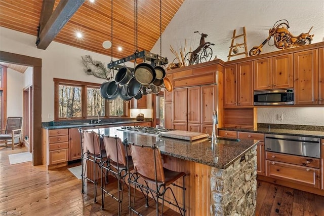 kitchen featuring a warming drawer, an island with sink, wood ceiling, and appliances with stainless steel finishes