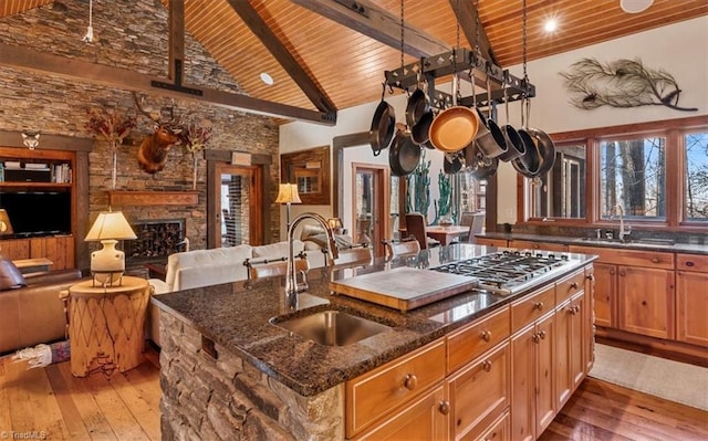 kitchen with a kitchen island with sink, open floor plan, a sink, and stainless steel gas stovetop