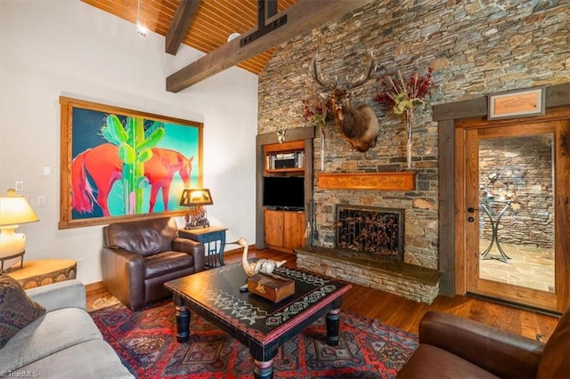 living area with baseboards, beamed ceiling, a fireplace, wood finished floors, and high vaulted ceiling