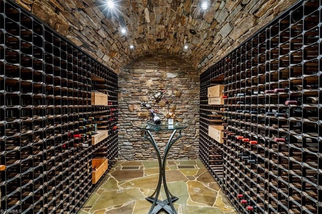 wine area with brick ceiling, stone flooring, and lofted ceiling