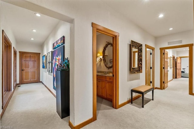 hall featuring a sink, recessed lighting, visible vents, and light carpet