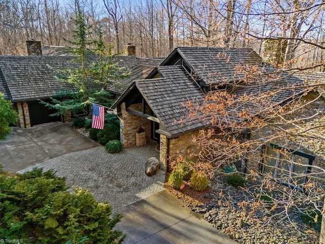 view of side of home with decorative driveway and stone siding