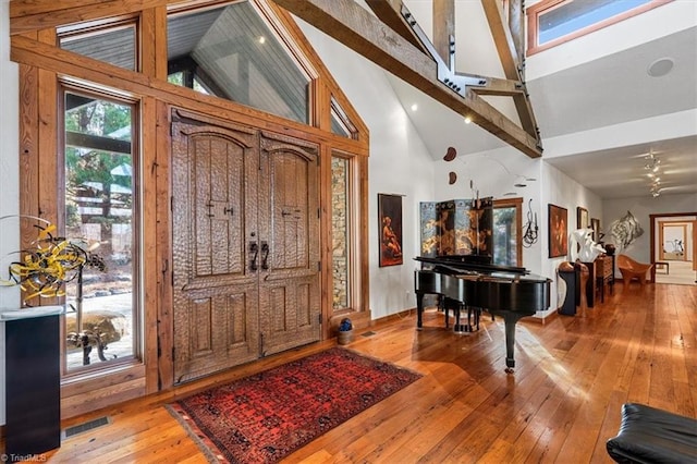 entrance foyer featuring beam ceiling, light wood-type flooring, visible vents, and high vaulted ceiling