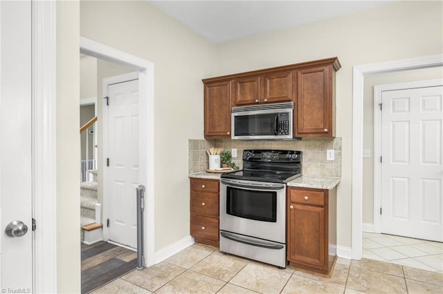 7255 Orchard Path Dr, Clemmons, NC 27012 - kitchen with appliances with stainless steel finishes, tasteful backsplash, light tile patterned floors, light stone counters, and brown cabinetry