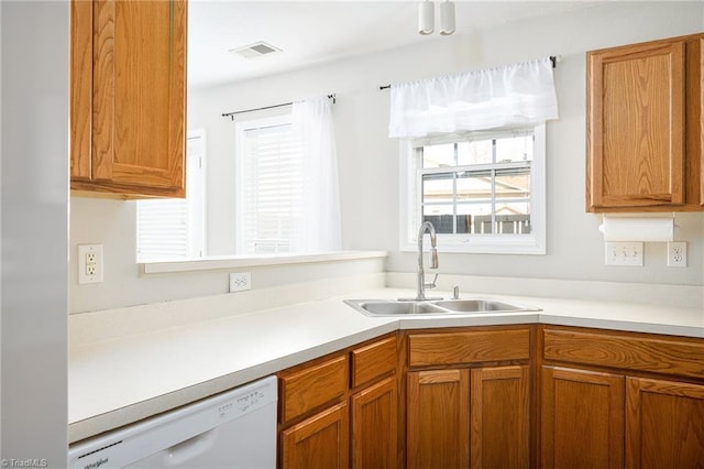 kitchen featuring light countertops, visible vents, white dishwasher, and a sink