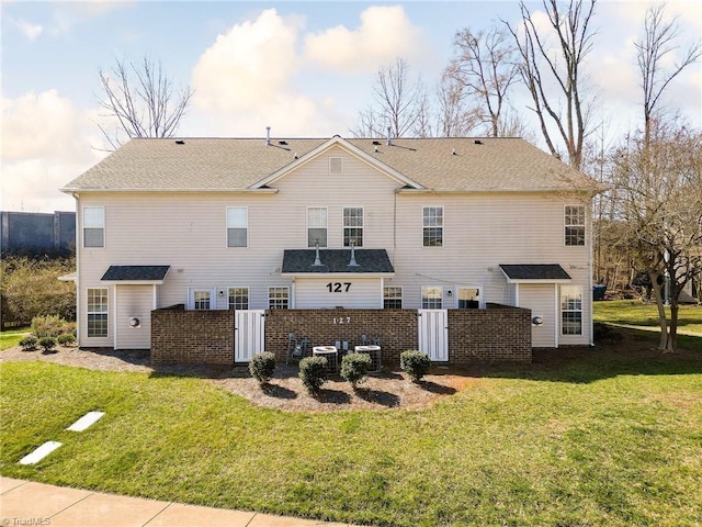 rear view of house featuring a yard, brick siding, and fence