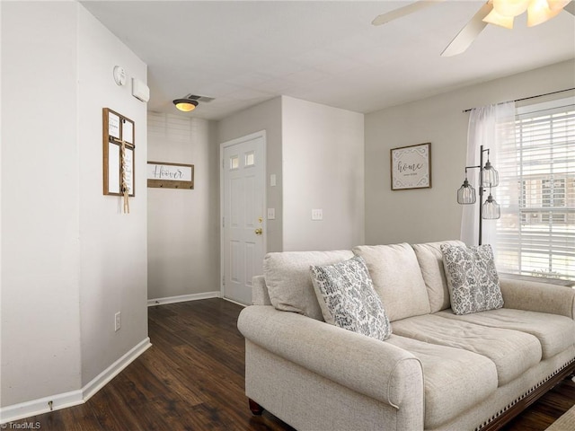 living room featuring visible vents, baseboards, wood finished floors, and a ceiling fan