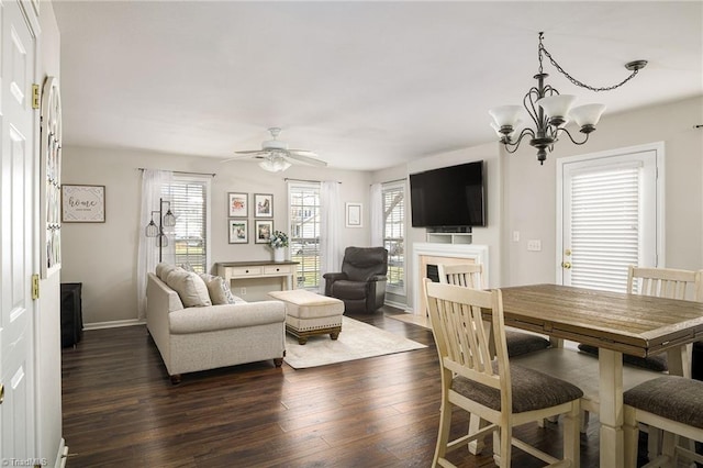 living room with dark wood finished floors, ceiling fan with notable chandelier, plenty of natural light, and a fireplace