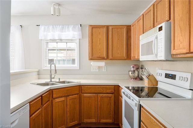 kitchen featuring a sink, white appliances, brown cabinets, and light countertops