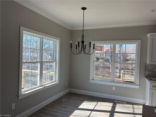 unfurnished dining area featuring ornamental molding, dark wood-type flooring, and a chandelier