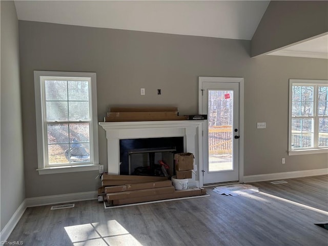 unfurnished living room with vaulted ceiling, a healthy amount of sunlight, and hardwood / wood-style floors