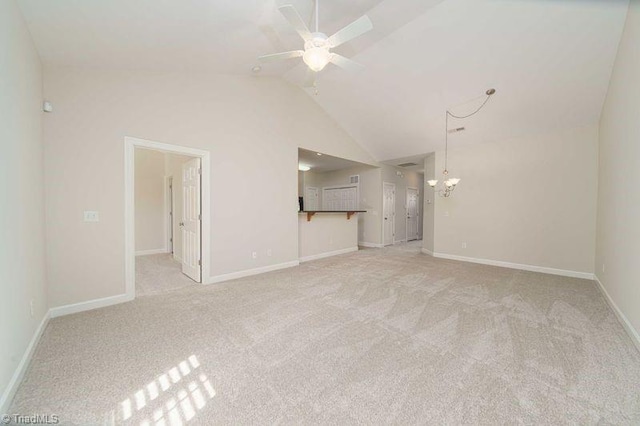 unfurnished living room featuring ceiling fan with notable chandelier, light carpet, and vaulted ceiling