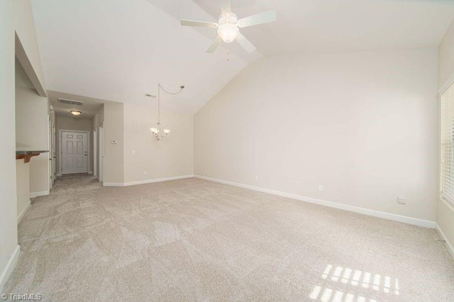 carpeted empty room featuring ceiling fan with notable chandelier and vaulted ceiling