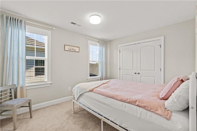 bedroom featuring a closet, light colored carpet, and multiple windows