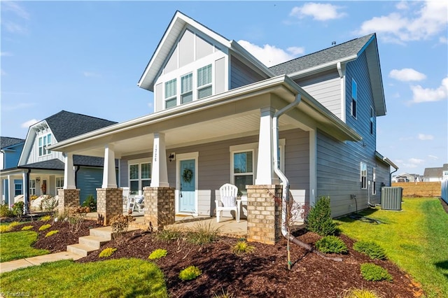 craftsman inspired home with central AC unit, covered porch, and a front lawn