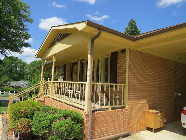 view of property exterior featuring brick siding and covered porch
