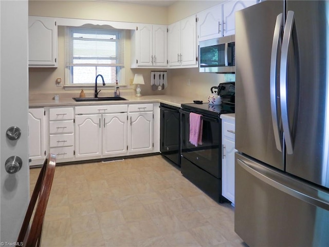 kitchen featuring appliances with stainless steel finishes, a sink, light floors, white cabinetry, and light countertops