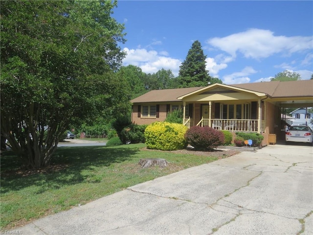 view of front facade with brick siding, concrete driveway, a carport, a front lawn, and a porch