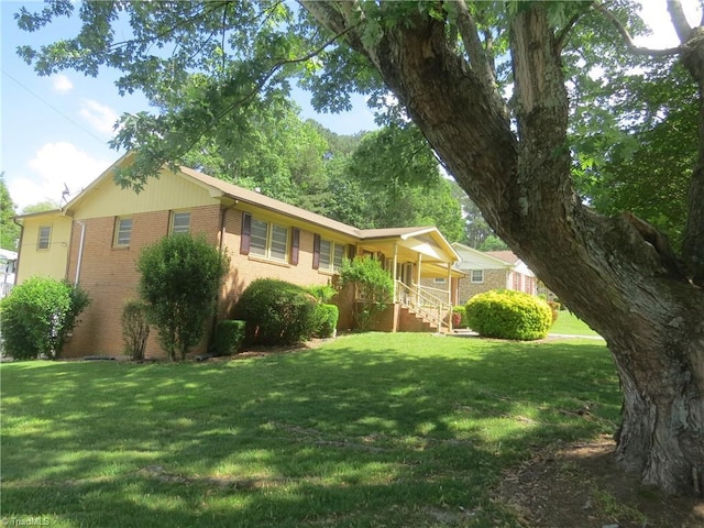 single story home featuring brick siding, a front yard, and a porch
