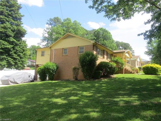 view of side of home featuring brick siding and a yard